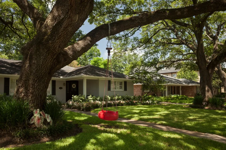 Small house with a red tire swing in front yard in Houston, Texas.
